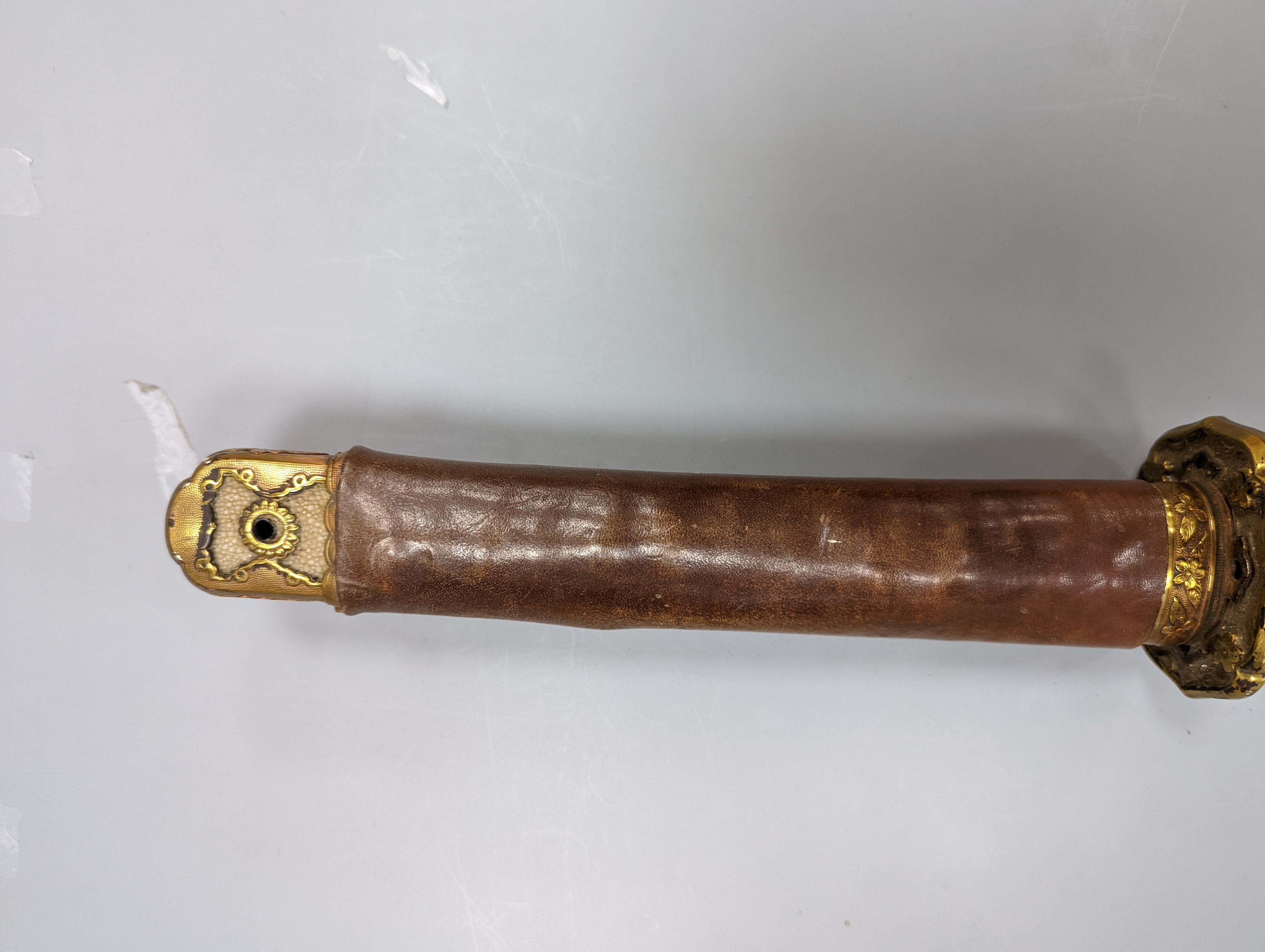 A Japanese Katana with leather covered sheath, plaque reading ‘Presented to Capt. S. Mear Telecoms B.M.A’ 93 cms long.